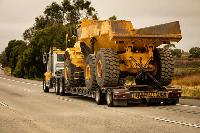 A very large dump truck being hauled by an 18 wheel truck
